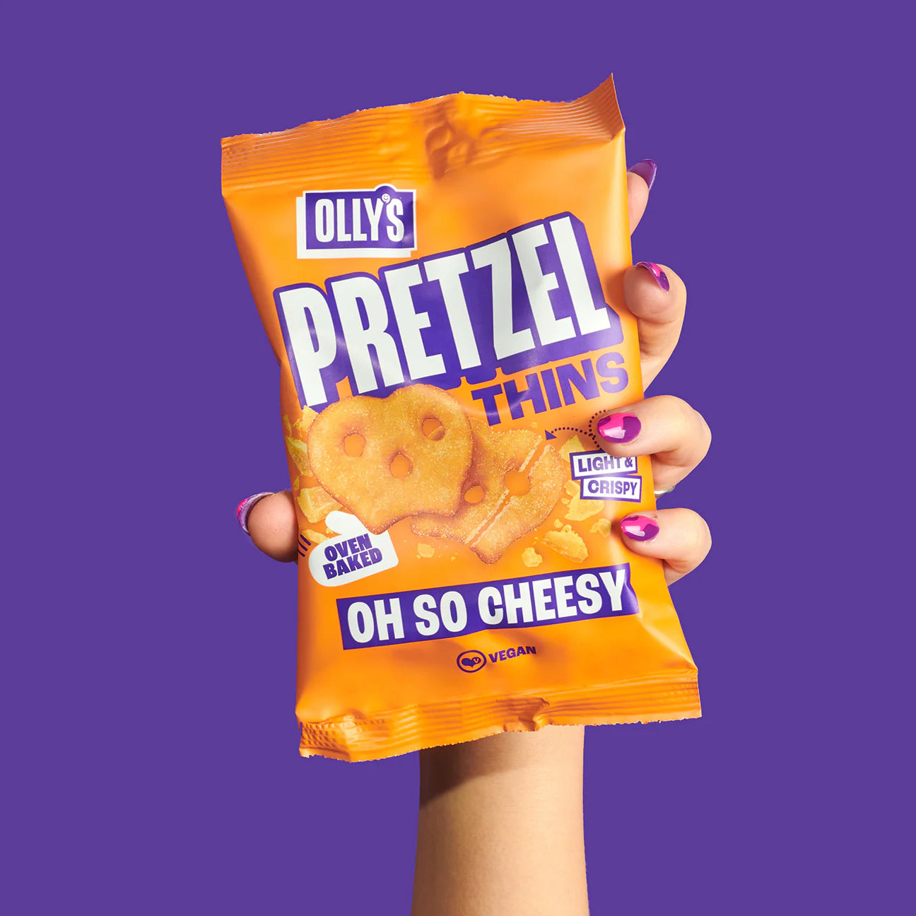 A hand with Olly's - Oh So Cheesy Pretzel 35g packet vegan and oven baked.