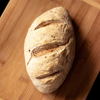 Loaf of bread on a wooden cutting board made using Mills & Folks - Bake-Free Sorghum bread flour mixture