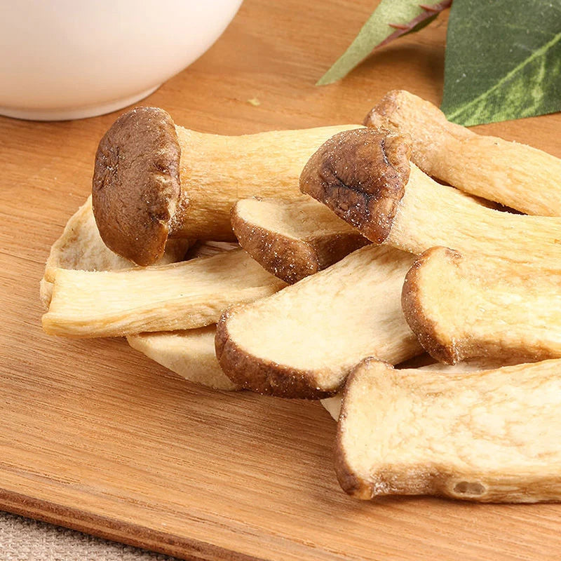 Raw shiitake mushrooms piled on a wooden cutting board,